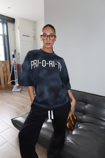 Priority: PRI-O-RI-TY tee SS25 – Zwart (Washed Black)